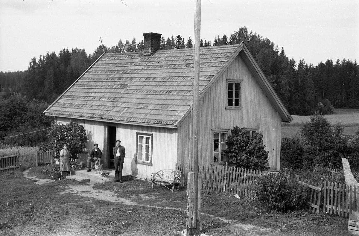 Tre personer foran våningshuset på bruket Nystuløkken på Krabyskogen. Personene er identifisert, som søsknene Villiam (til høyre), Anna og Sigurd Johansen. Serie på fem bilder.