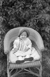 Barneportrett. Barnet, som er uidentifiset, sitter i en kurv