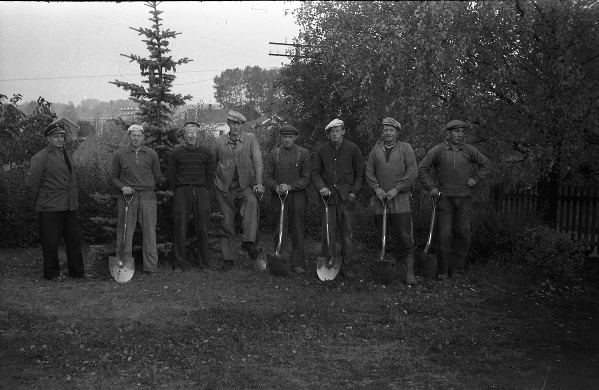 En gjeng grøftegravere fotografert på gårdsplassen på Odberg på Kraby, oktober 1950. Karene gravde grøft for telekabel. Ingen av karene er identifisert.