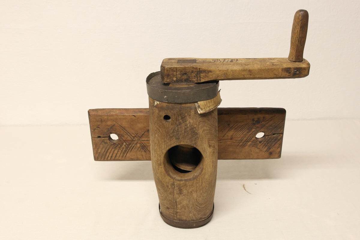 Potetkvern i tre. Kverna er laget av to trestokker som er hulet ut og satt sammen med jernbånd i begge ender. Skrue/Kall inni hulrommet, påmontert ei sveiv på utsiden. Kverna er festet til ei fjøl. Initialer og årstall er inngravert i sveiva.