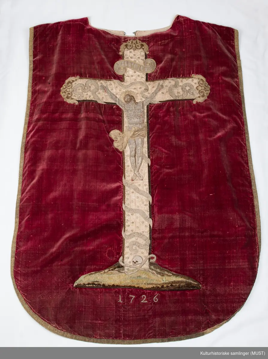 Korsfestelsen: Jesus på korset, teksten INRI over og en hodeskalle i underkant. Årstallet 1726 er brodert på.