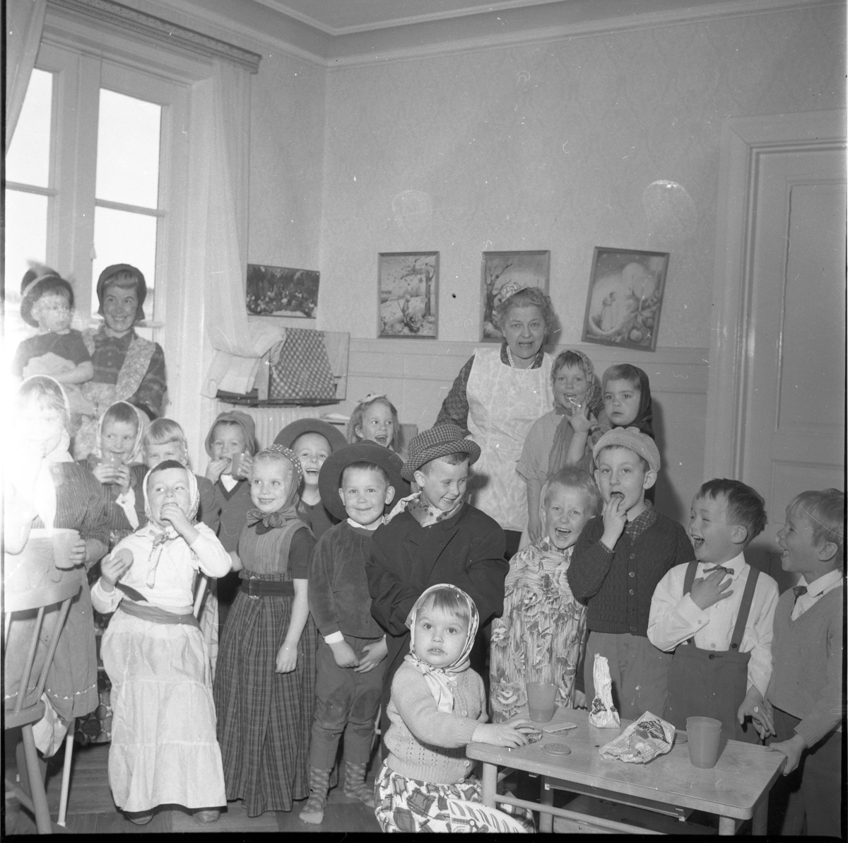 Lekskolan i Gränna 1963. Den äldre kvinnan i ljust förkläde är Anna-Lisa "Nalle" Lundin. Okända maskeradklädda barn, möjligen påsktid.