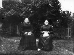 To kvinner med strikketøy, sitter ute i hagen