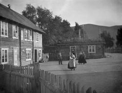 Folk og gårdstun ved vegen.