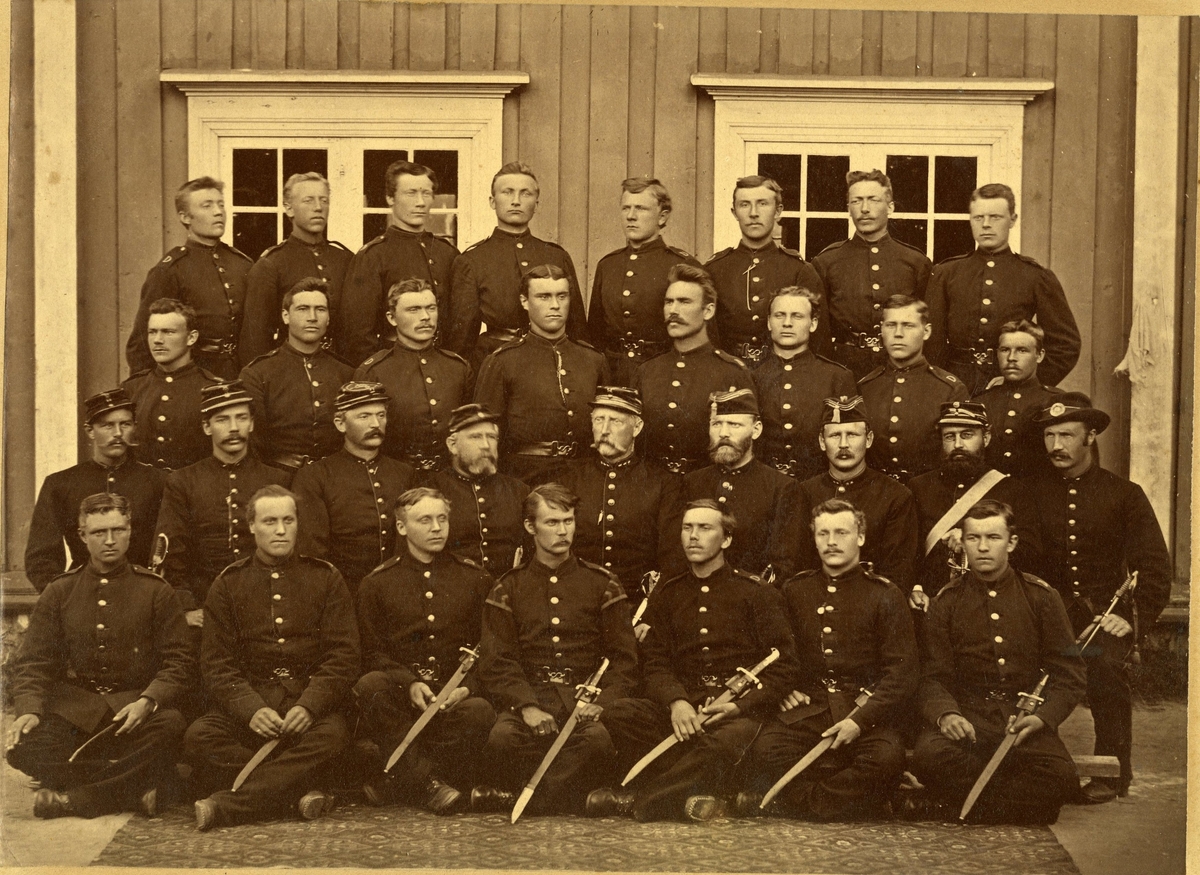 Gruppebilde av sergentklasse ifra 1884 iført uniform og paradesverd.
Navn bak på bildet. Det er en musiker på bildet. Første rekke i midten med "salereder"-Øverlie.