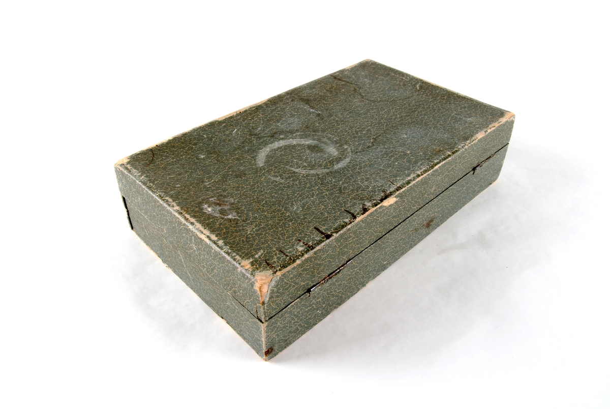 Smykkeskrin med hengsler og lås. Innsiden er foret med rødt silketøy. Et speil er festet på innsiden av lokket.