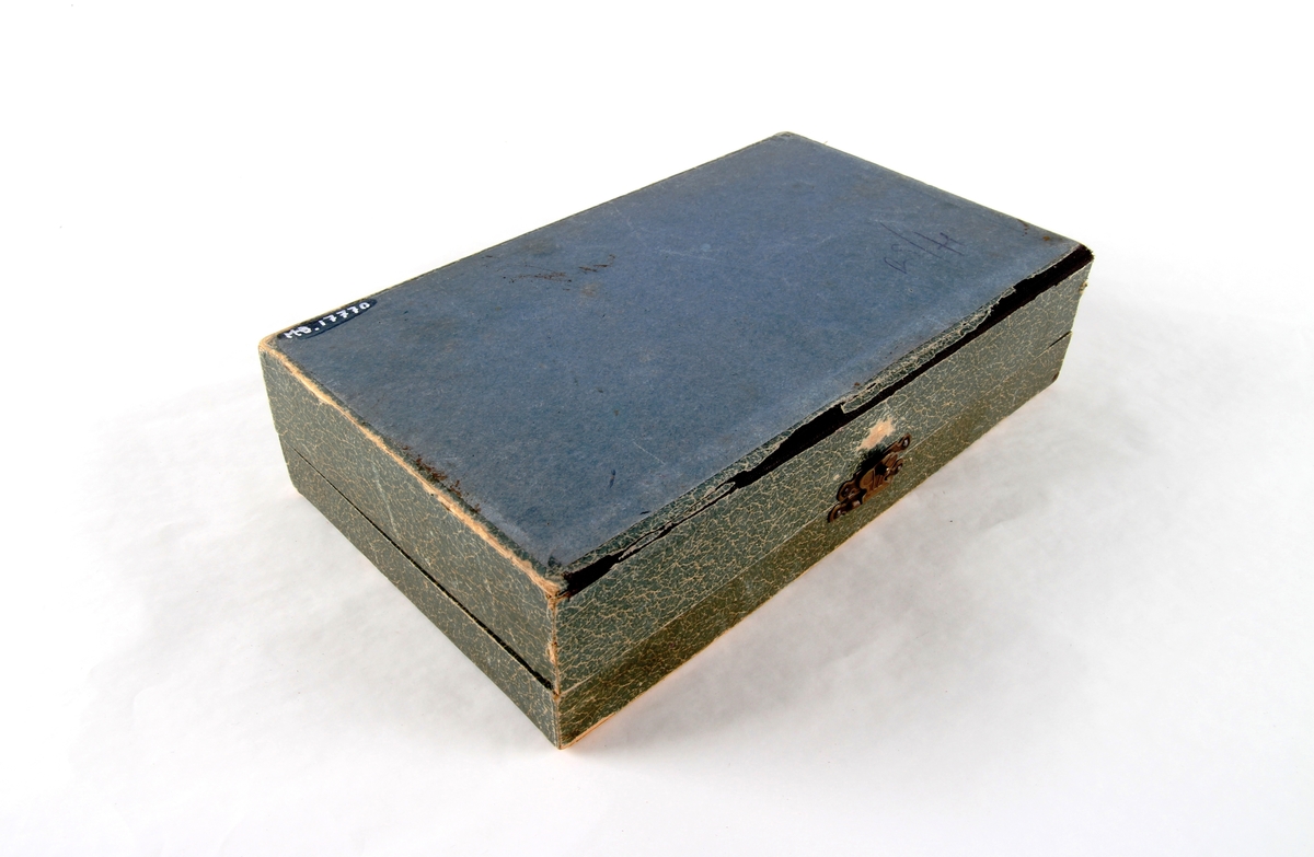 Smykkeskrin med hengsler og lås. Innsiden er foret med rødt silketøy. Et speil er festet på innsiden av lokket.