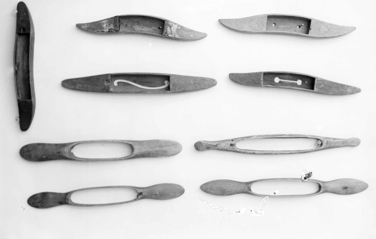 Avlang og buet vevskyttel av tre, med uthuling i midten der det er festet en trådspole av metall.