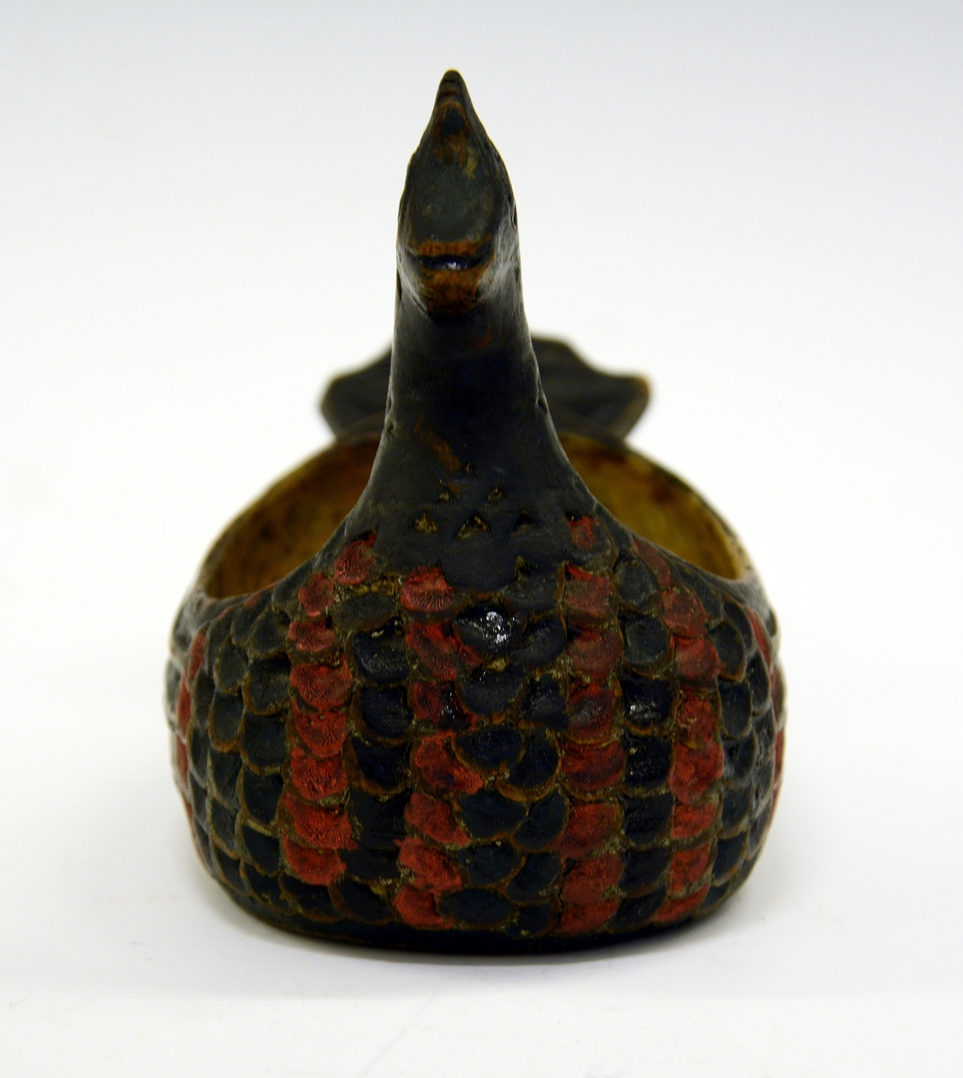 Ølhøne. Fra protokollen: Koks, liten og høneformet, malt. Hovedet kort, med kam, brystet skaaret i fjærskjæl, siderne i vinger, halen kerbsnit. Under skaaret "Birgiet 1774". Malt i rødt og blaagrønt, gult indeni.