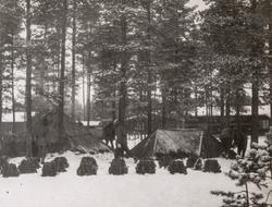 Soldater med kneppetelt. Oppstilte ryggsekker i forgrunnen, 