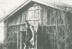 En eldre mann stående utenfor en gammel stue. Mannen er Ole 