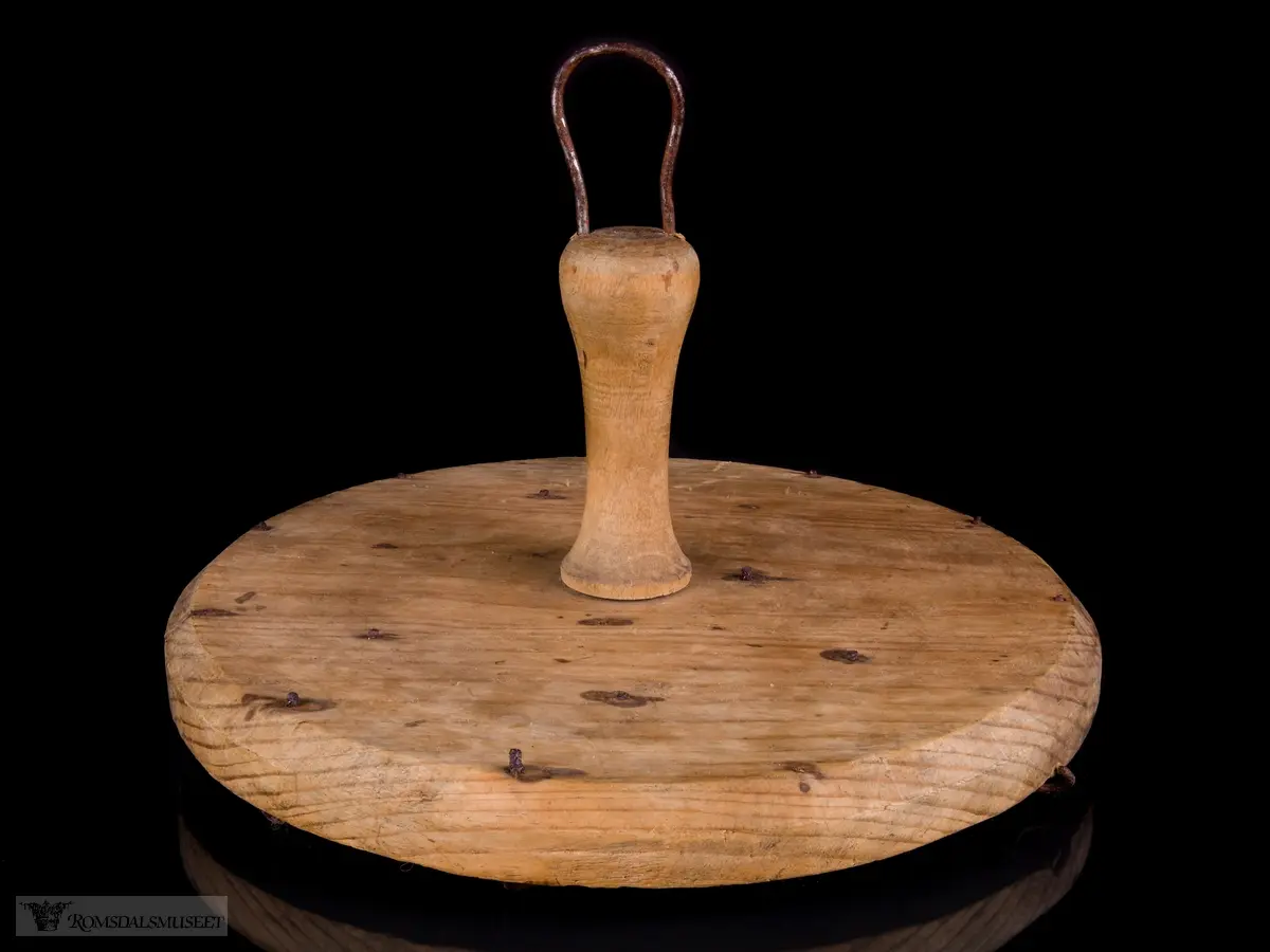 Sirkulær treplate med en dreid trehåndtak med metallhempe. Flere metallkroker er festet på undersiden for festing av lysveker.