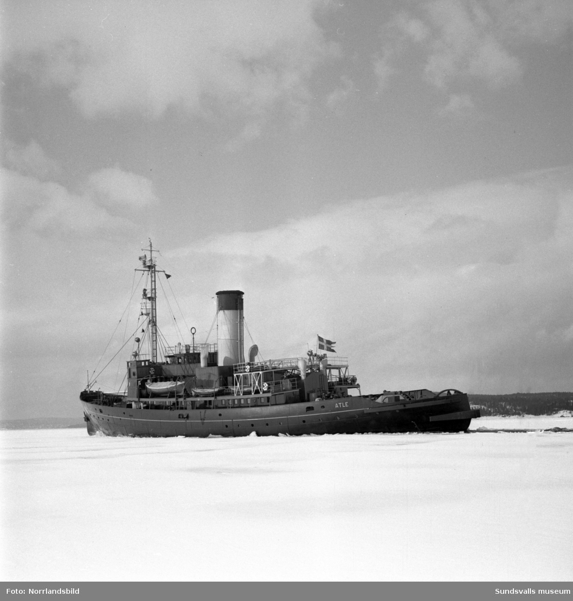 Isbrytaren Atle bryter isränna för Stockholmsbåten Wiros förbi fyren Draghällan och in mot Sundsvalls hamn.