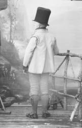 Mann med gammel drakt. Flosshatt, kort jakke, knebukser, hos