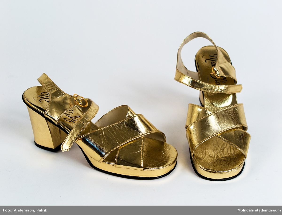 1 par guldfärgade sandaletter i storlek 37. Tillverkade i Italien.  
Skorna är köpta i Lindome skoaffär, cirka i slutet av 1940-talet - 1960-talet.

I skon finns texten: "Made in Italy"
Under sulan finns gjuten text: 
"MADE IN ITALY   
37"
