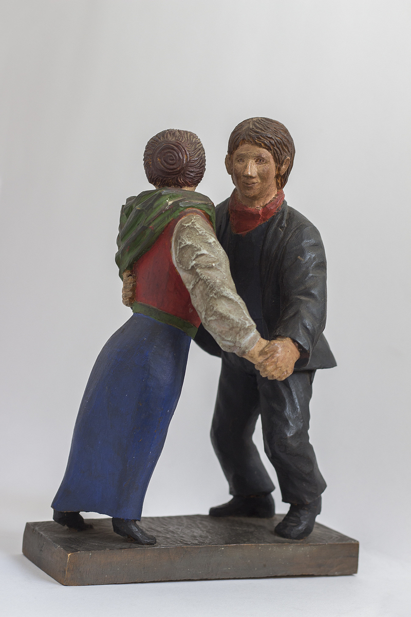 Treskulptur av par som danser på plint.