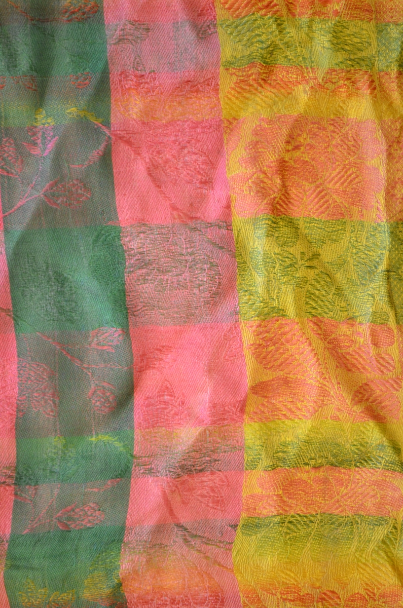 Tørkle i silkedamask i grønt, rosa, gult. Små frynser av renning og innslag rundt kantane.