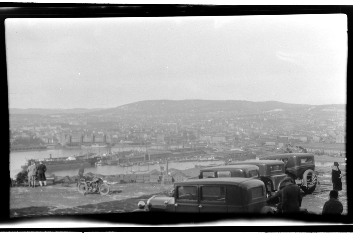 Flere biler står parkert på Ekeberg med utsikt mot Oslo. Fotografert 1930.