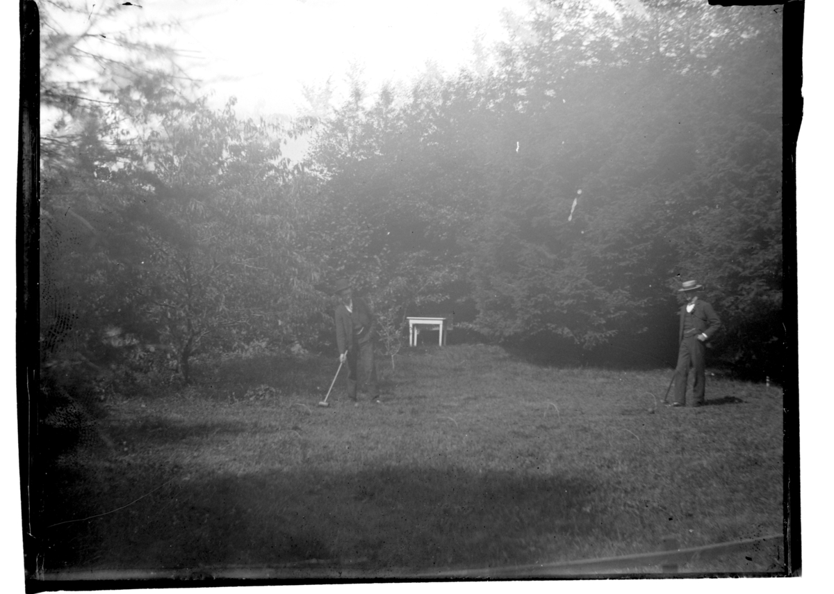 To menn spiller crocket i en hagen på Farøy.