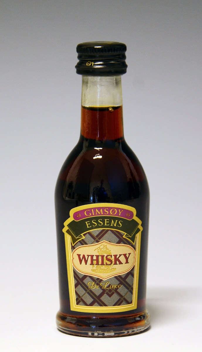 Liten, klar glassflaske med whiskyessens. Etikett med påskrift foran og bak.