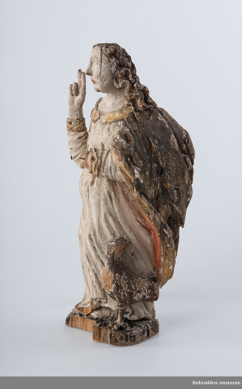 Skulptur, apostelbild från 1600-talet som tillhör altartavla UM000393.
Krederat trä med mager oljefärg och oljeförgyllning. Förgyllningen uppvisar båda bladguld, slagmetall och/eller silver.

Ur handskrivna katalogen 1957-1958:
Apostelbild, Lane Ryr 
H. 40 cm; Kristus, höger hand höjd t. välsignande åtbörd, vänster bär ett klot; färgen delvis flagn; sprickor.
Krederat trä med mager oljefärg och oljeförgyllning. Förgyllningen uppvisar båda bladguld, slagmetall och/eller silver.
Lappkatalog: 13

Se foto på föremålet i Uddevalla museums kyrkliga utställning 1920, UMFA54467:0422.

Ytterligare en kyrklig skulptur är märkt med inventarienummer UM394, aposteln Johannes med välsignelsegest och en örn, manteln är har rödmålad insida. Denna skulptur återfinns emellertid inte på äldre bilder av altartavla UM000393, den äldsta fotot UMFA916 samt ett yngre fotografi, UMFA917 som är taget i kyrkliga utställningen av Maria Lundbäck, och alltså inte kan vara senare än år 1927.

Ur Nationalencyklopedin, NE.se:  Apostel
I konsten framställs apostlarna alltid barfota samt klädda i tunika och mantel. De bär oftast en bok samt sitt individuella attribut, i allmänhet respektive martyrredskap (Petrus bär dock himmelrikets nycklar).