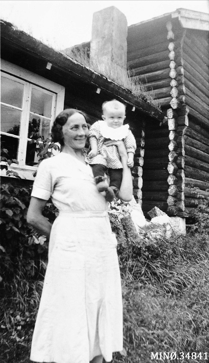 Kvinne og gutt foran det gamle eldhuset på Nord-Fløtten i Tylldalen.