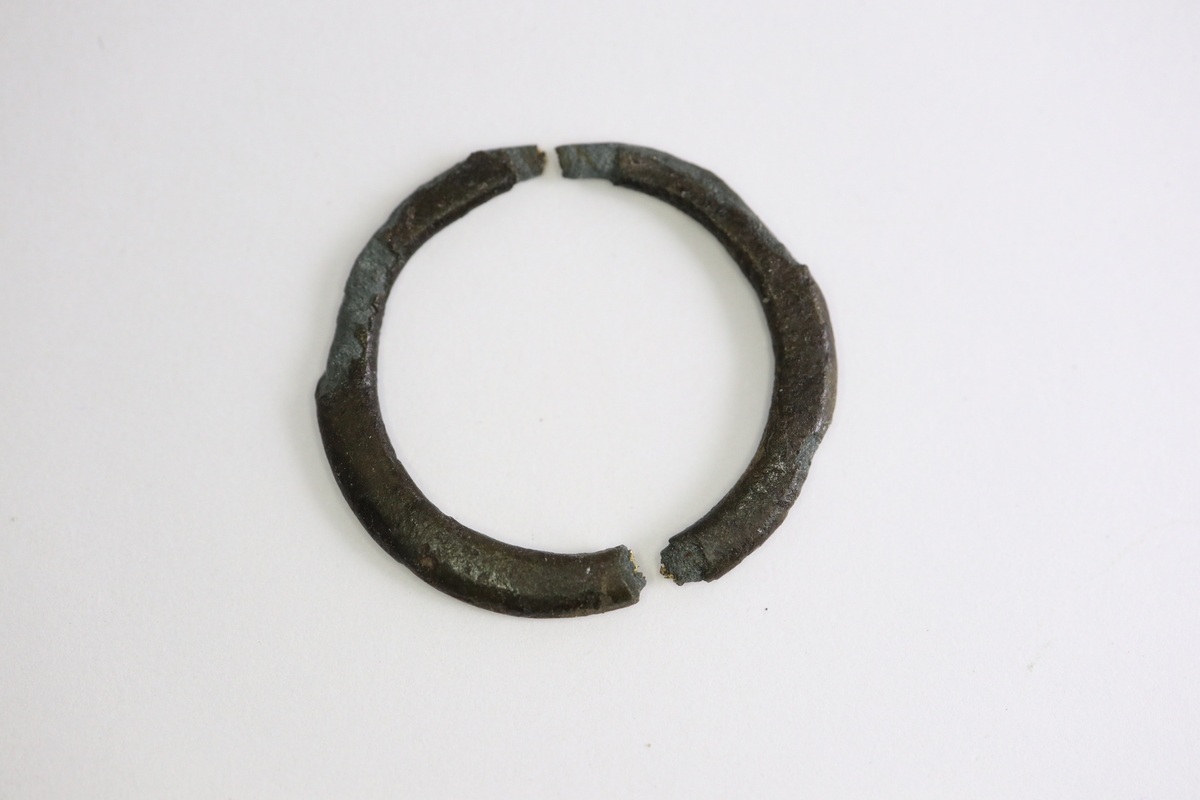 Bronsring, möjligen en fingerring, med något ovalt tvärsnitt. Itubruten.