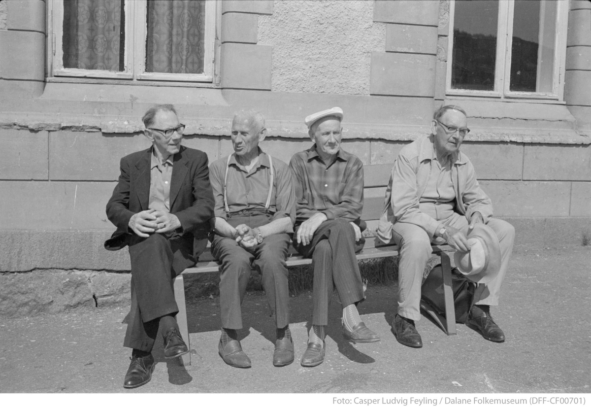 Fire menn sitter på en benk utenfor rutebilstasjonen ved Jernbanekaien i Egersund