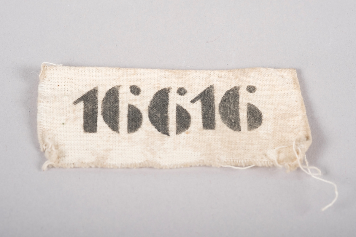 Merkelapp i naturhvitt lerretsstoff med nummeret 16616 trykket på med sort blekk. Fangnummer 16616 viser til Bjørn Harder som satt på Grini fra 1944 til 1945.
