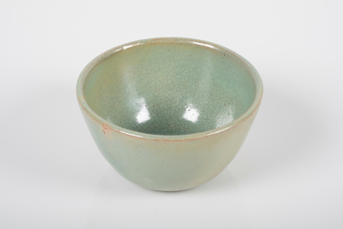 Kopp keramikk med grønn lasur. Buet hank på koppen. Bunnen har matt overflate.