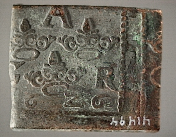 1- öre
Fyrkantigt mynt.
Åtsidan: tre kronor placerade i V-form. Versalerna G A R delvis synliga. Placerade i upp och nedvänd V-form med G till vänster, A ovanför och R till höger om kronorna.
Det fyrsiffriga präglingsåret - längst ner på myntet - är 1626.
Ocentrerad prägling. Ram delvis synlig.
Frånsidan: två korsade pilar under en krona.
Till vänster om pilarna siffran 1, till höger versalerna ÖR.
Centrerad prägling. Ram delvis synlig.
Nuvarande skick: åtsidan sliten.
Vikt: 26,5 gram.

Text in English: Square-shaped coin. Denomination: 1 öre.
The obverse side has three crowns spaced in a V-shape, partly legible. The initials G A R, which appear in capital letters, are placed in a triangular formation, faintly legible, with G placed to the left, A above and R to the right of the crowns.
The four digit year of coinage, 1626, is placed beneath the crowns and the initials.
The coin stamp is off-centre. The frame is partly visible.
The reverse side has two crossed arrows beneath a crown.
To the left of the arrows is the numeral 1, to the right the initials ÖR.
The coin stamp is centred. The frame is partly visible.
Present condition:  the obverse side is worn.
Weight: 26,5 gram.