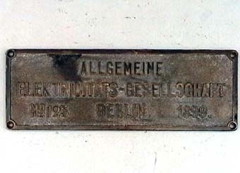 Rektangulär skylt av mässing med text i relief:
"Allgemeine Elektricitäts - Gesellschaft Nº 125".