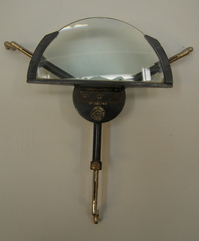 Instrument av mässing målad i svart kulör som tillhört ångfärjan Starke. Mitt på instrumentet är ett förstoringsglas fastsatt med ett gångjärn av mässing.