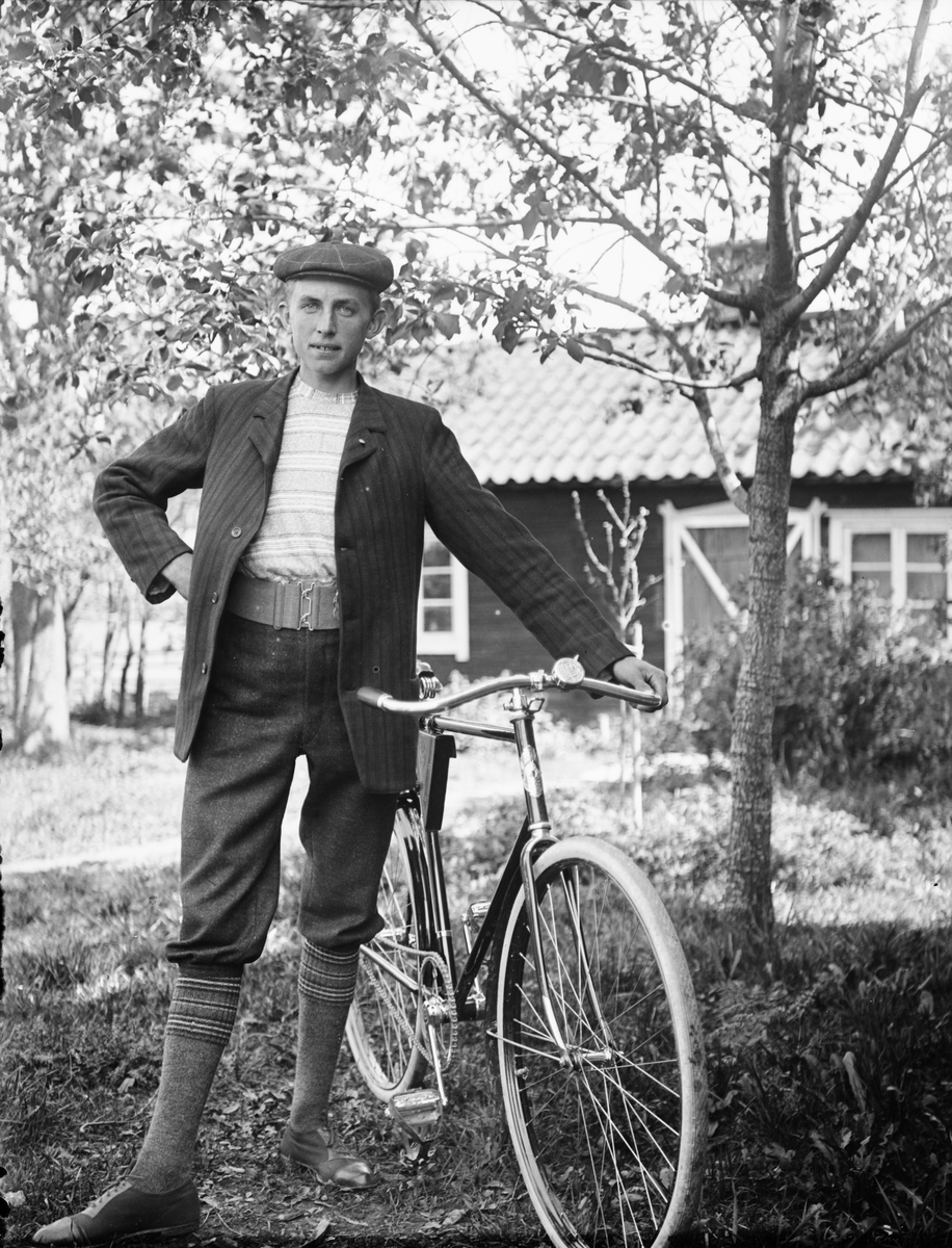 Man med cykel i trädgård, Sävasta, Altuna socken, Uppland