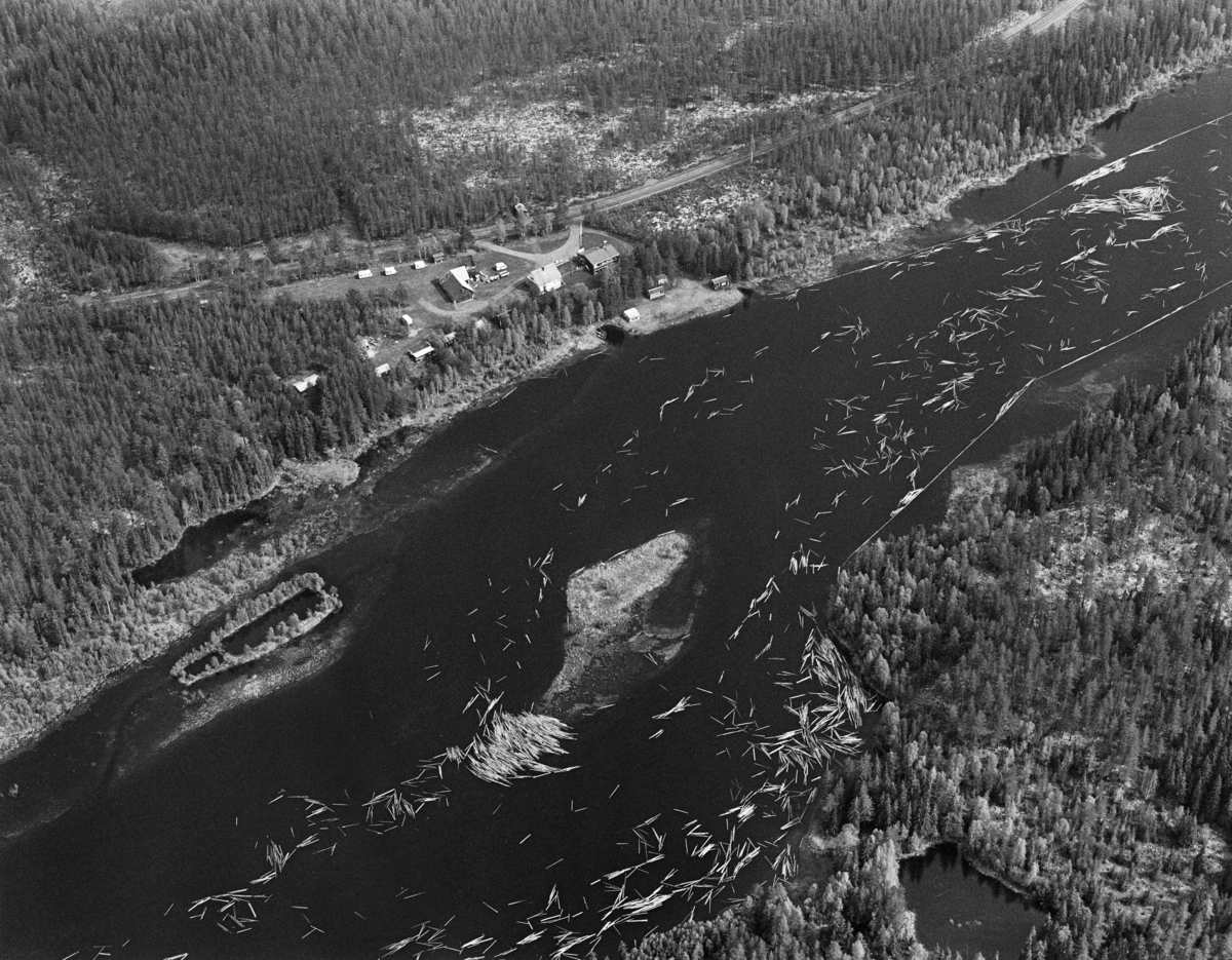 Flyfotografi tatt over elva Søndre Rena i Åmot i Hedmark i mai 1984, den siste sesongen det foregikk tømmerfløting i denne delen av Glommavassdraget.  Fotografiet er tatt nord for den oppdemte Løpsjøen og det stedet der elva Søndre Osa renner inn i Renavassdraget.  Sentralt i bildet ser vi den lille, flate Granholmen.  Vi ser også at det har dannet seg en haug på grunna nord for holmen, og i ei vik vest for den.  Lengre nede (til høyre i bildet) later det til at fløterne hadde lagt lenser – en flytende kjede av tømmerstokker – som hindret fløtingsvirket i å legge seg mot land.  I den øvre delen av bildet skimter vi Desetvegen (Fylkesveg 607).  Mellom den og elveløpet ser vi et lite gardsbruk.