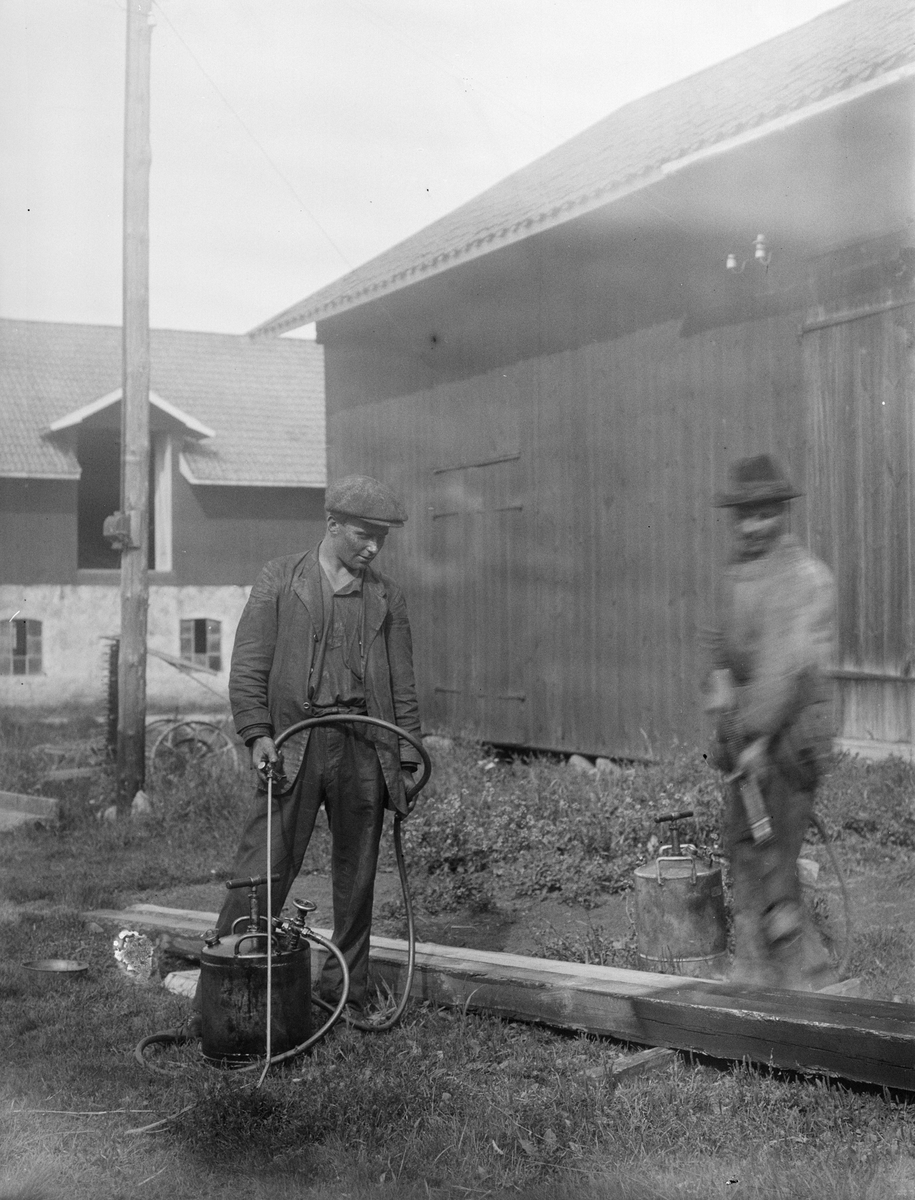 "Erik och Albert Anderson impregnerar stolpar", Sävasta, Altuna socken, Uppland 1923