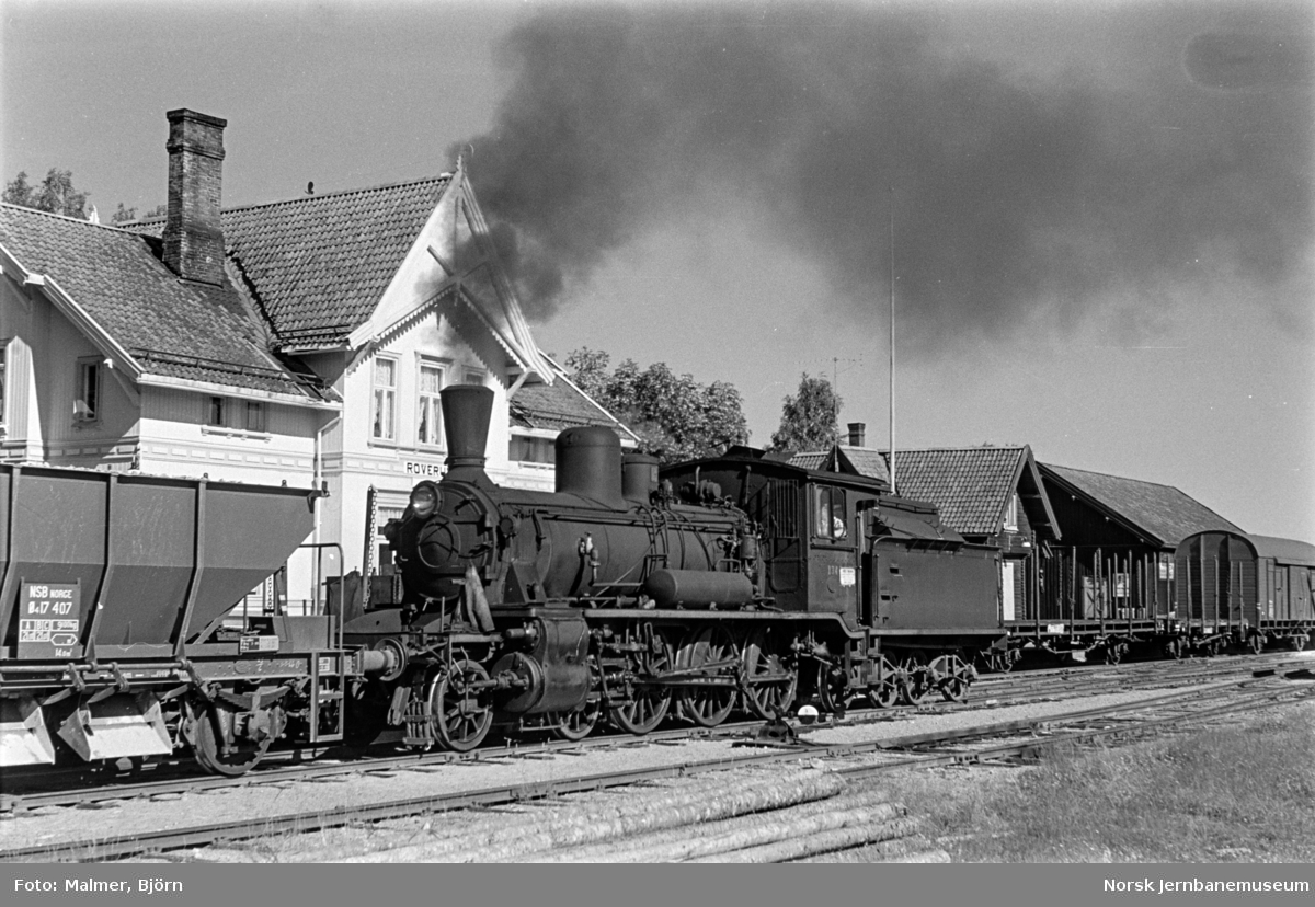Grustog trukket av damplokomotiv type 18c nr. 134 i spor 2 (nærmest) på Roverud stasjon. I spor 1 står kryssende godstog.