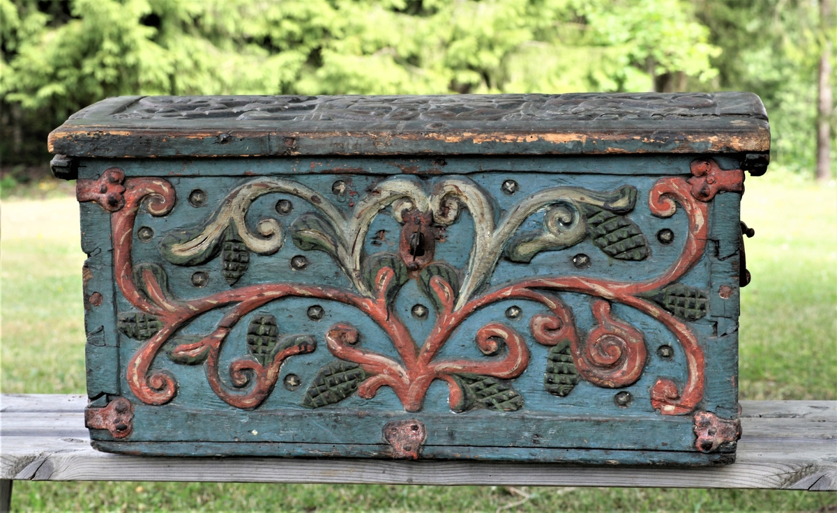 Kista er blåmalt, rikt utskåret på lokk og sider, blader og kongleliknende blomster, på lokket bladkrans og prestekrageliknende ornament utskåret i rødt, grønt og hvitt
Kirkeskrin i barokk1650-årene, antagelig skåret i Lesja eller Romsdalen