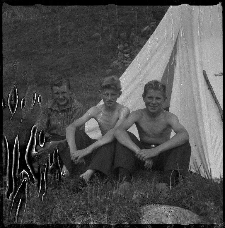 Styrhuset til lastebåten "Zita" i fart, med grus eller sand ombord. Det er også bilder av familien Skjold og tre gutter foran et telt. På bilde nr. 5 er Frida Johannessen nr. 2 fra venstre.