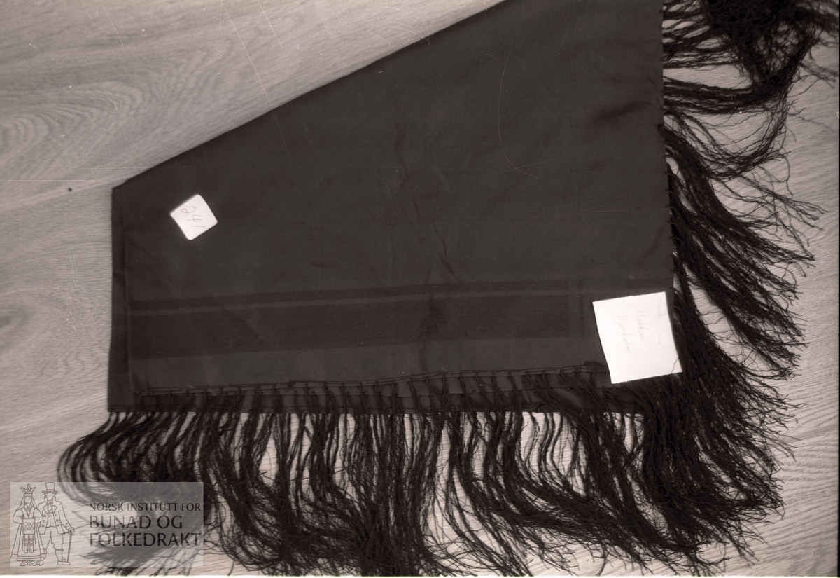 I svart silke med stripebord i sateng.  Svart tafs.  72,5  x  7,5 cm.