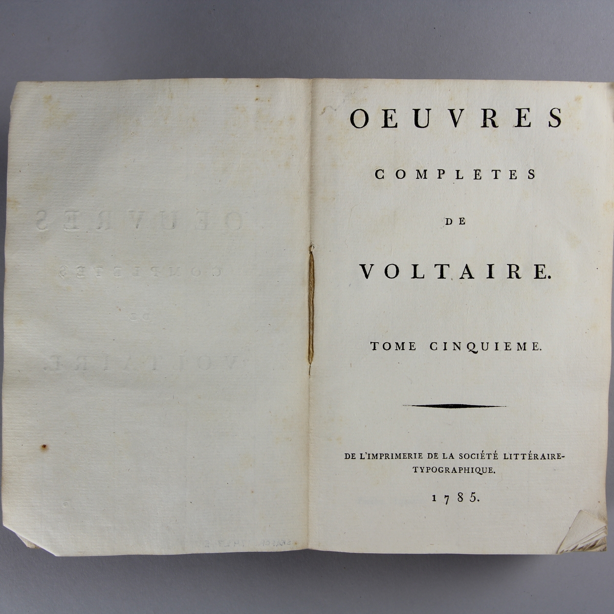 Bok, häftad,"Oeuvres complètes de Voltaire." del 5, tryckt 1785.
Pärm av gråblått papper, skurna snitt. På ryggen pappersetikett med tryckt text med volymens namn och nummer. Ryggen blekt.