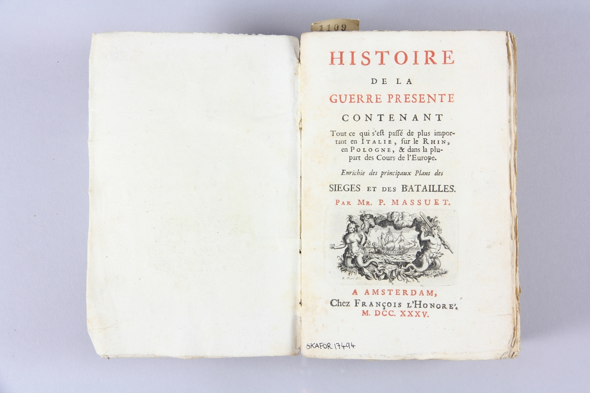 Bok, pappband, "Histoire de la guerre presente", tryckt 1735 i Amsterdam. Pärmar av marmorerat papper, blekt rygg med påklistrade etiketter med närmast utplånad text. Oskuret snitt. Graverade plascher.