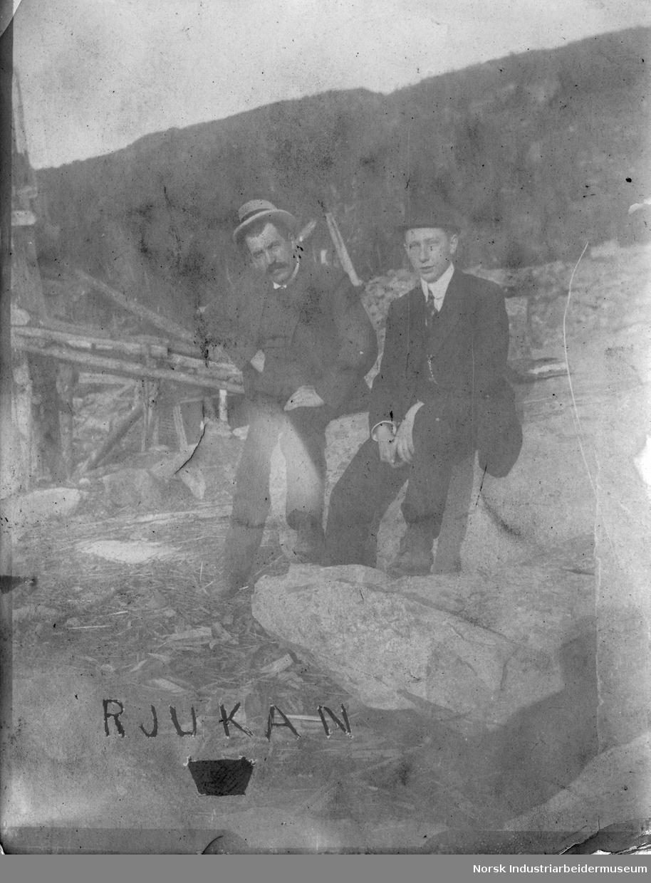 To menn sitter på stein.
