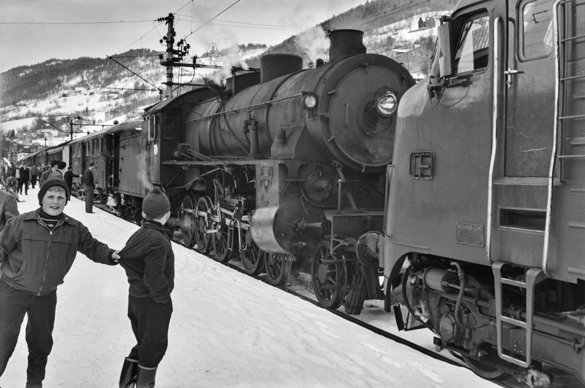Dagtoget fra Bergen til Oslo Ø, hurtigtog 602, på Voss stasjon. Toget trekkes av damplokomotiv type 31b nr. 402 (forspann) og diesellokomotiv type Di 3 nr. 620 (ekstra forspann).