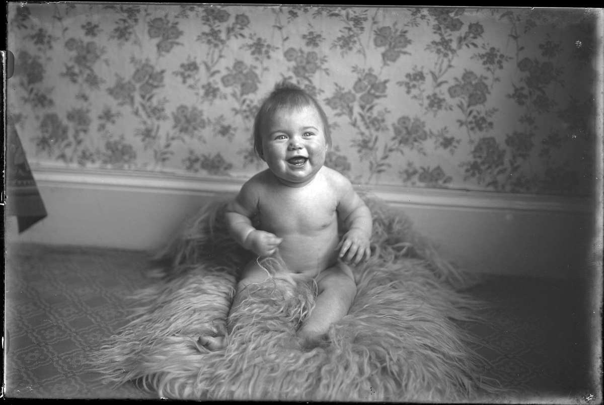 Ett litet barn sitter på en fäll. I fotografens egna anteckningar står det "Paul Anderssons dotter". Tolkat som Gunvor Linnéa Andersson.