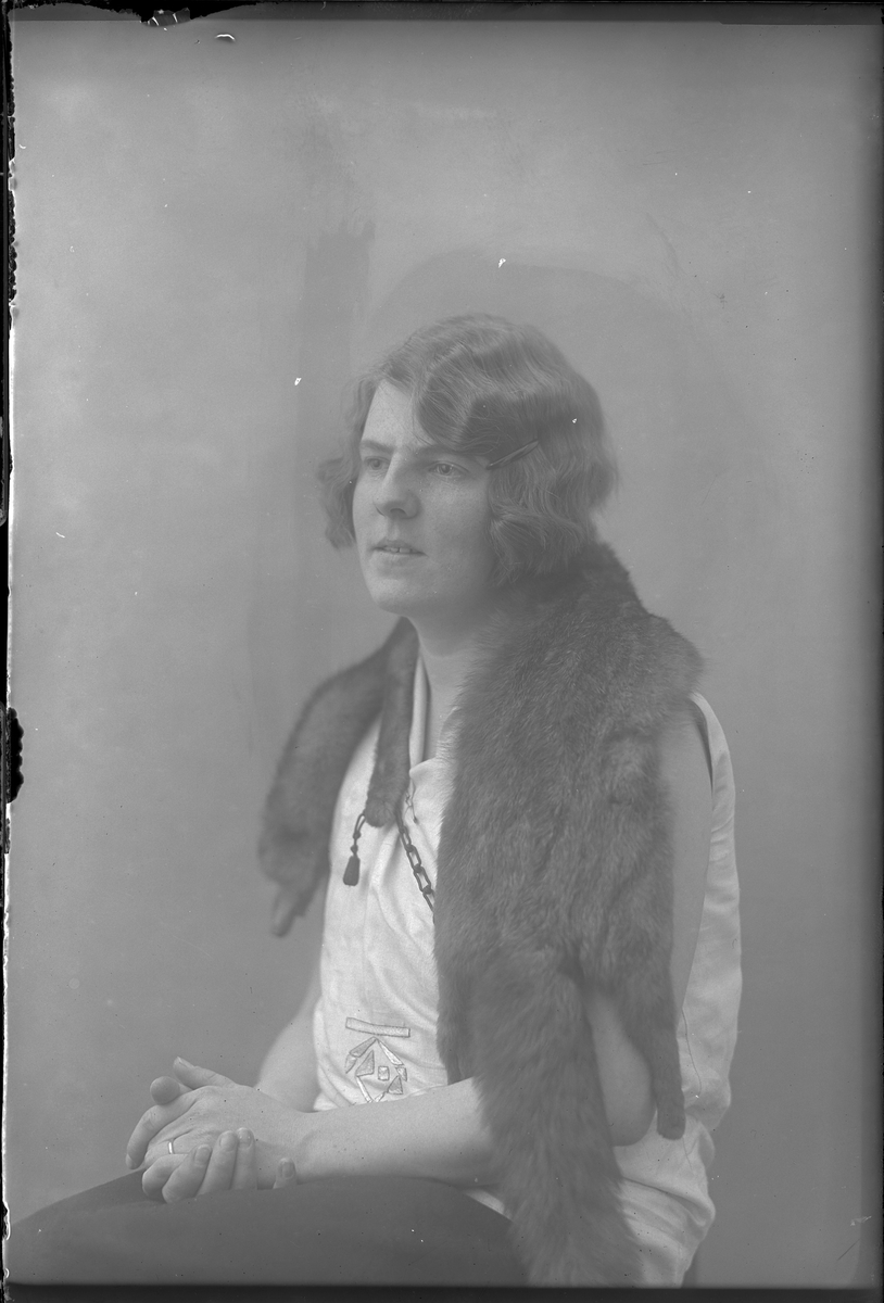 Porträtt av Lizzie Skoglund med vit blus och en räv om axlarna.