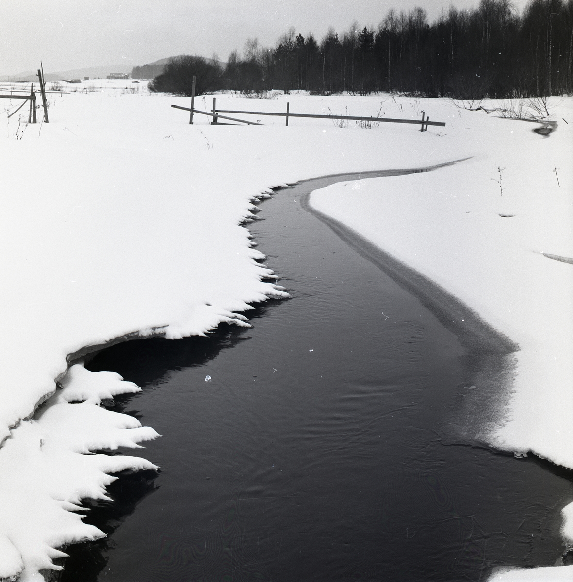 En smal ränna av Glösboån sticker fram under snön den 8 april 1956.