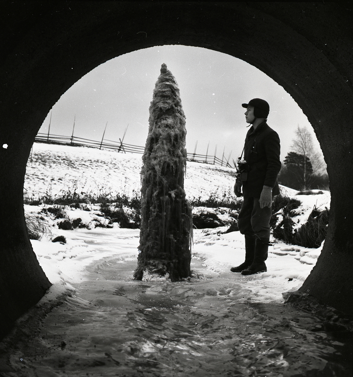 En man står intill en ispelare vid Peranders bron den 19 december 1957.