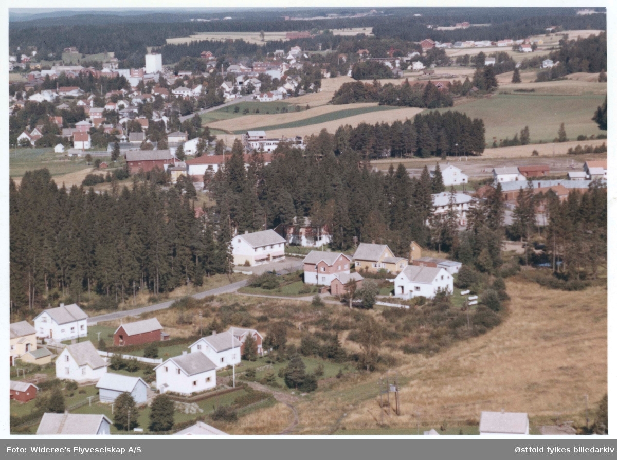 Skråfoto av boligfeltet Bergenhus, 11. sept. 1963. 
Butikken Bergenhus Handel ligger midt i motivet.

Rakkestadbyen sees i bakgrunnen.