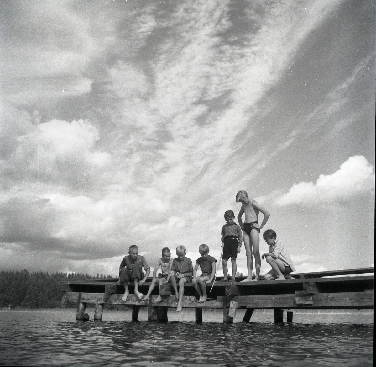 Sju stycken barn metar från en brygga, sommaren 1947.